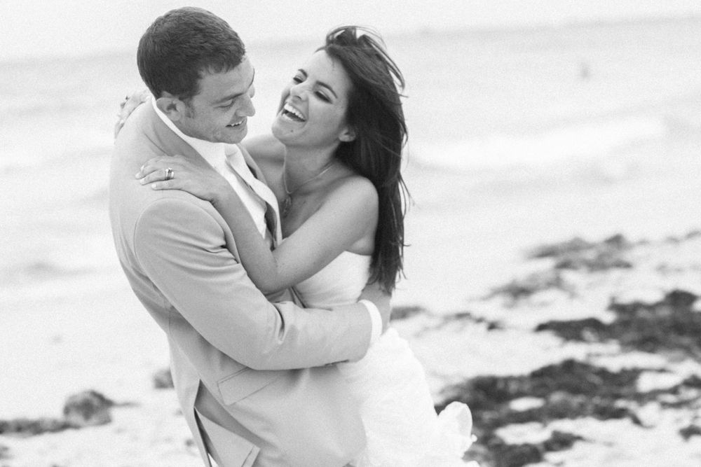 A romantic black and white beach photoshoot featuring a couple embracing on the sand near the ocean.
