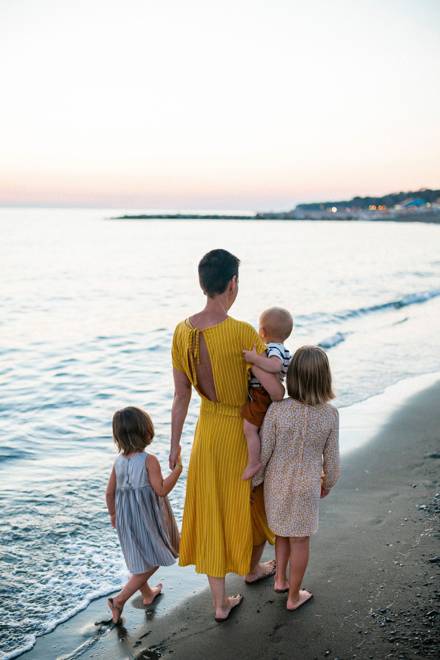 Family walking together along the beach at sunset by the ocean waves.