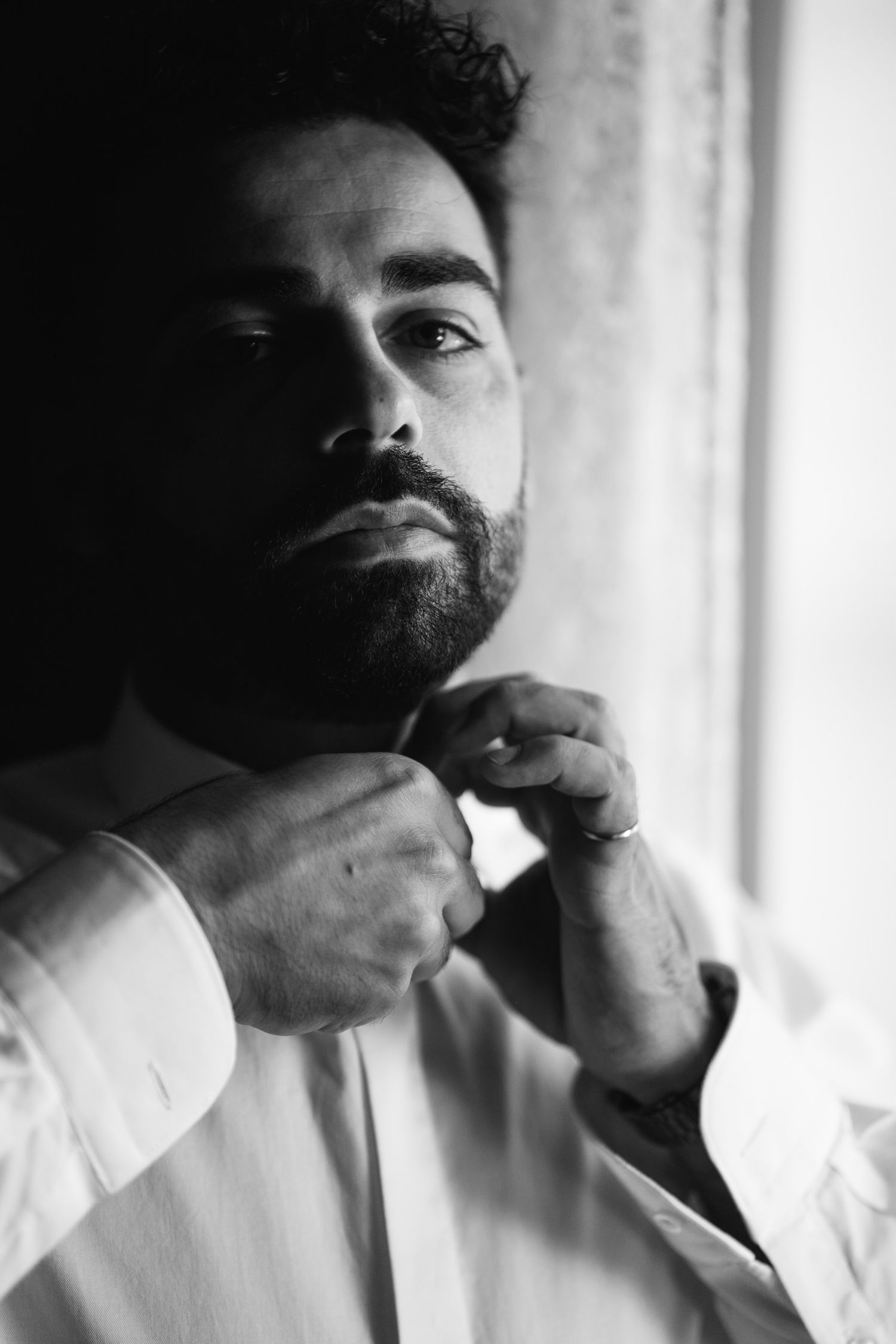 Black and white portraits showing someone touching their face near a window.
