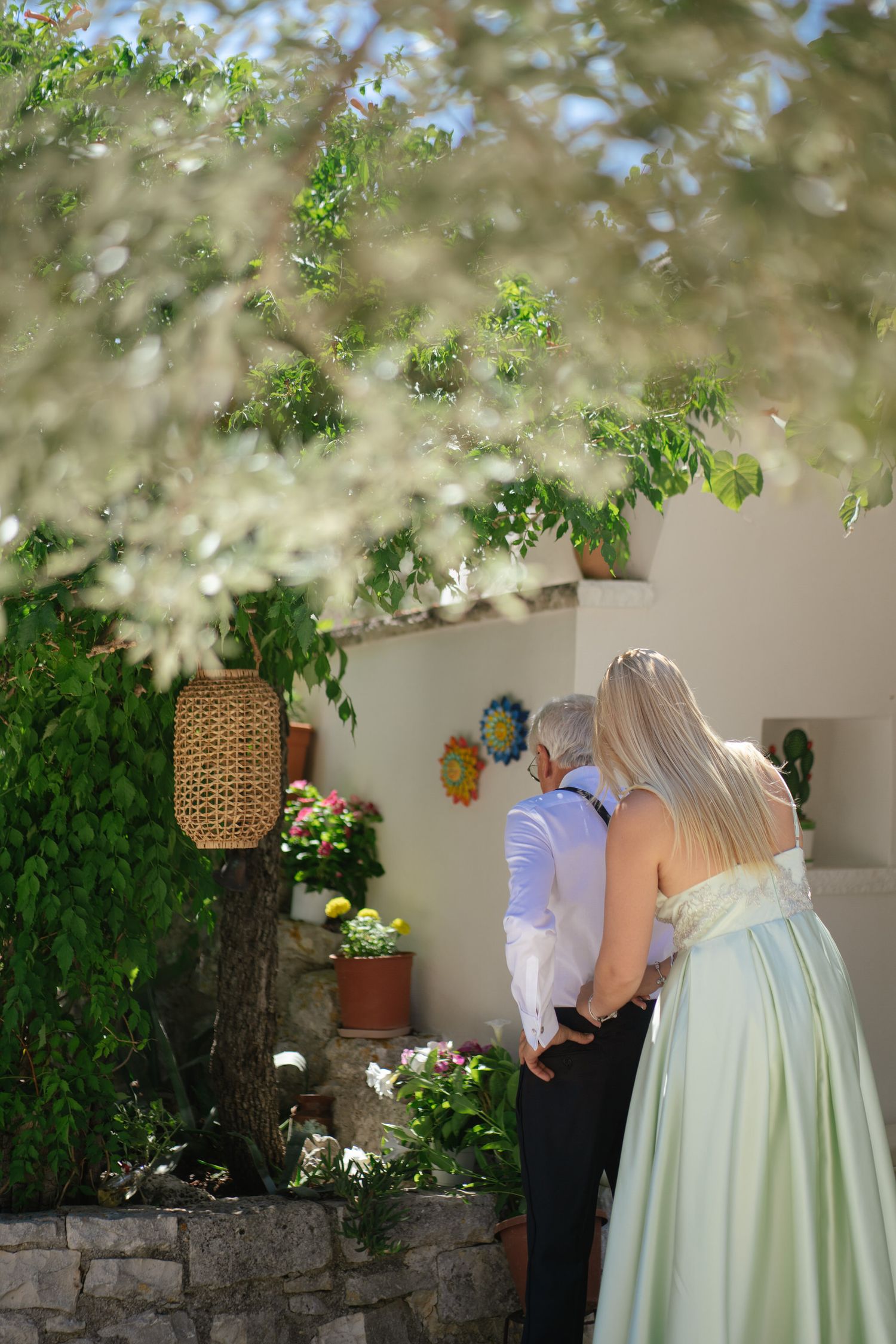 Garden wedding scene with mint green dress against stone wall and hanging greenery.
