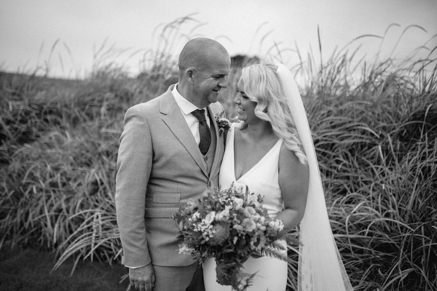 Black and white portrait of wedding couple in natural grass setting.