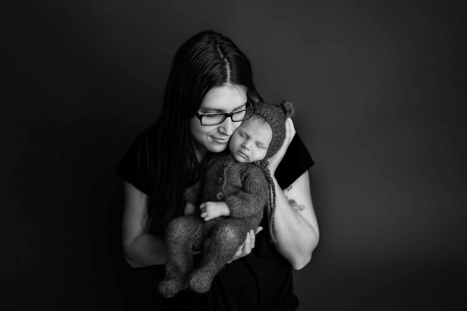 Black and white studio portrait capturing gentle family interaction.