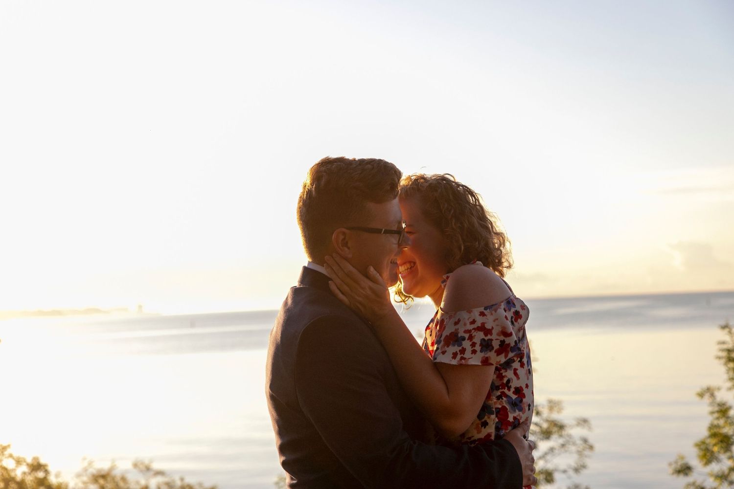 a couple at sunrise embracing one another with their heads close