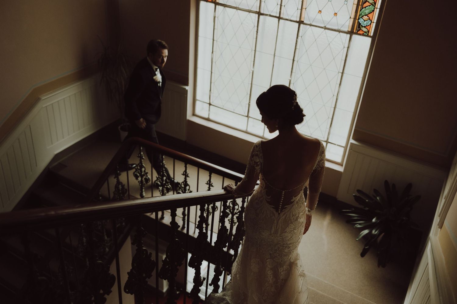 Silhouette on a staircase near a window in moody natural lighting.