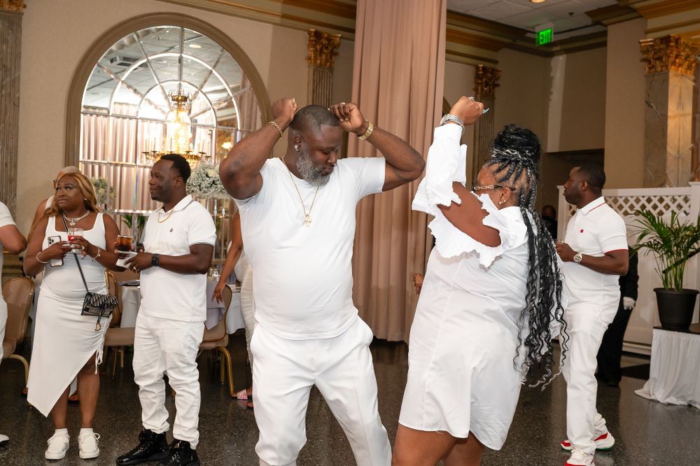 Wedding reception dance floor with guests in all-white attire enjoying festivities.
