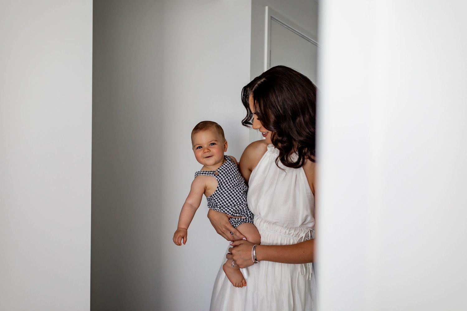 A tender moment captured in a bright white room with soft natural lighting.