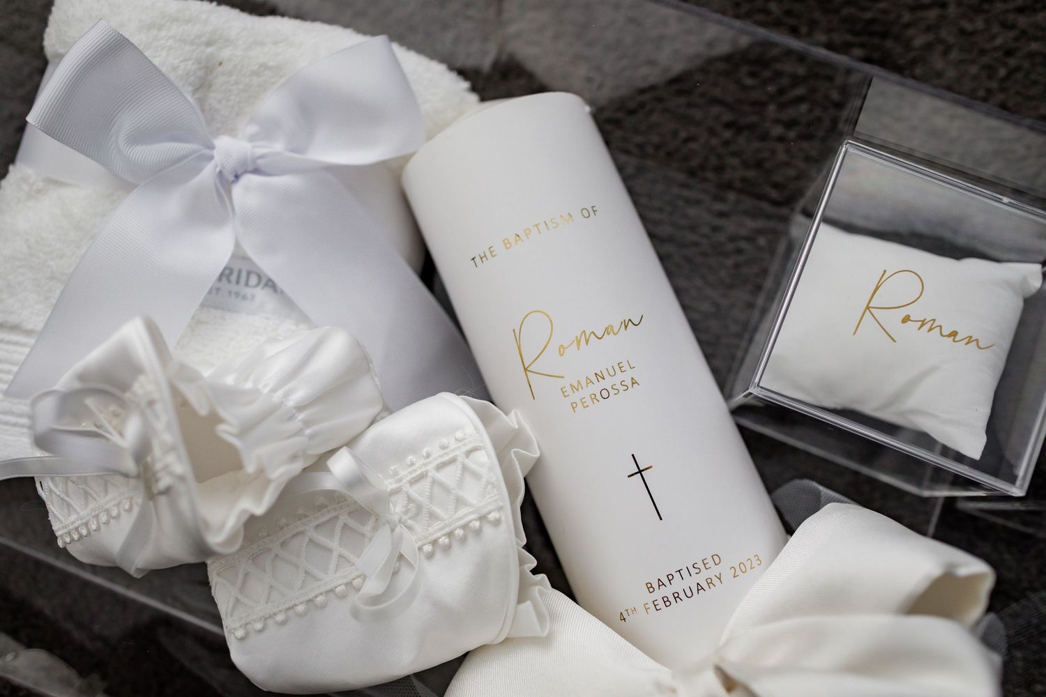 White christening accessories and religious items arranged with a decorative bow.