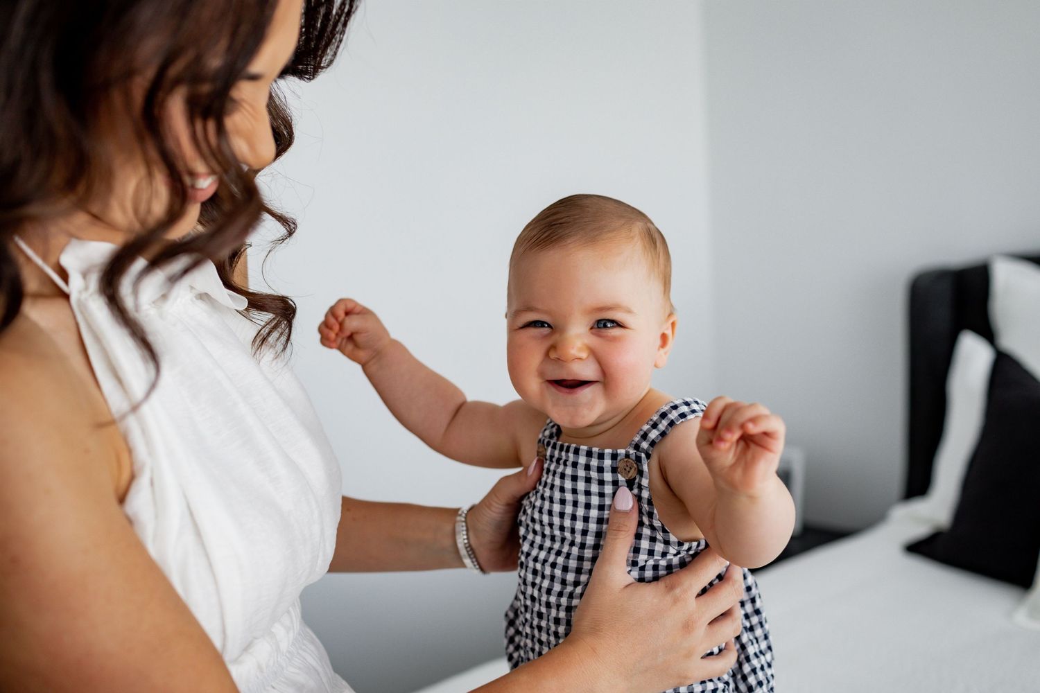 A joyful moment shared in a minimalist white bedroom setting.