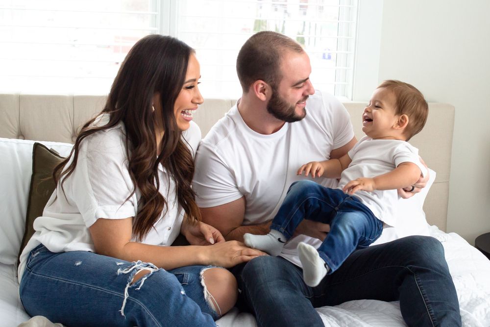 Mother, Father and toddler sitting on a bed portrait