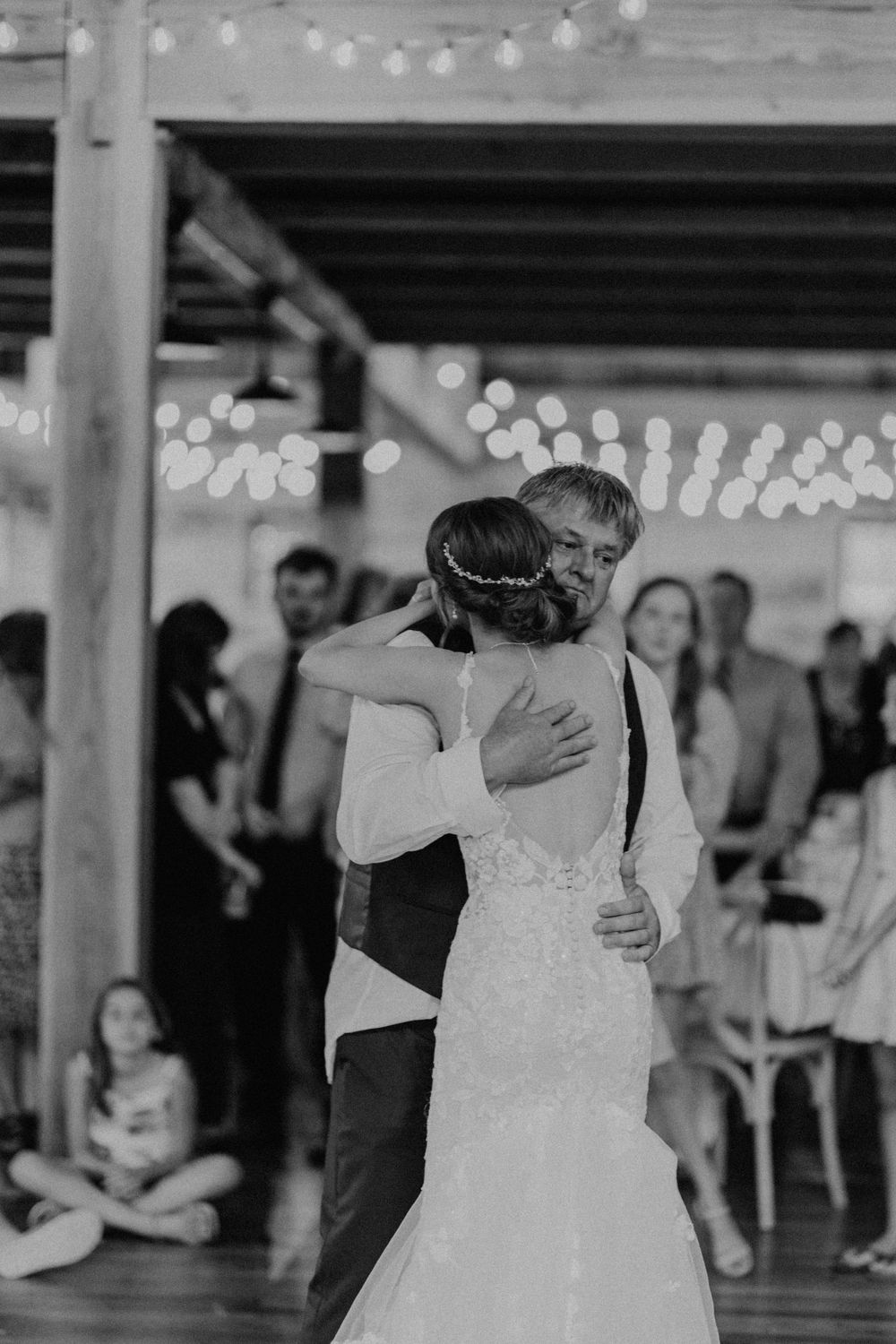 Black and white photo of bride embracing her father during an emotional father-daughter dance at wedding.