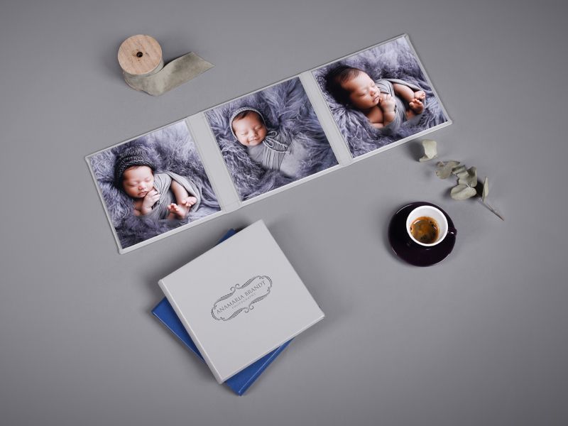 Professional photo prints and album layout with coffee cup and decorative elements on grey background.