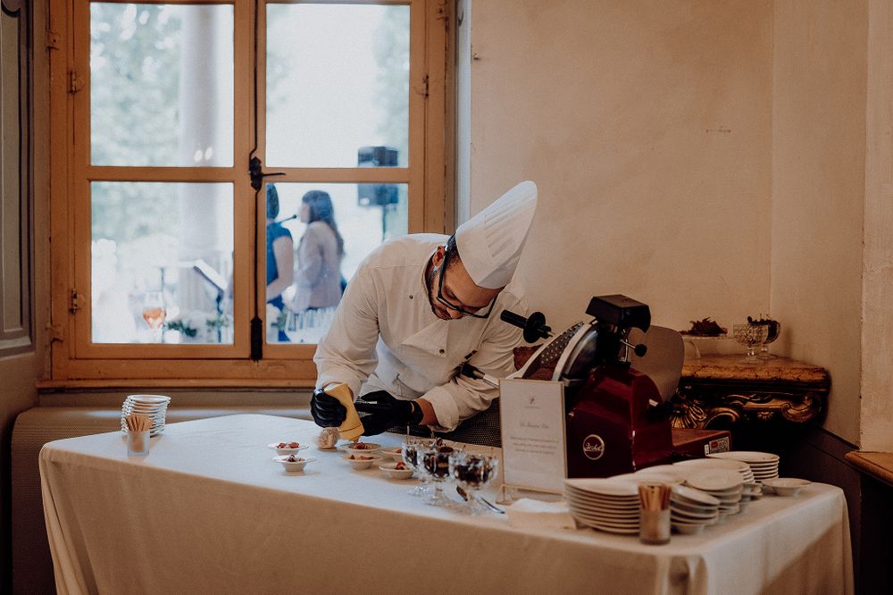 Chef in white uniform preparing elegant desserts at a beautifully arranged table during a wedding reception.