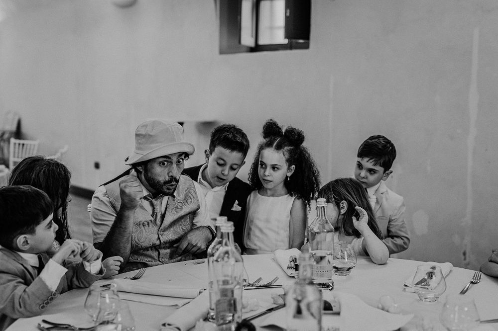 Black and white photo of wedding entertainer performing magic trick for group of delighted children.