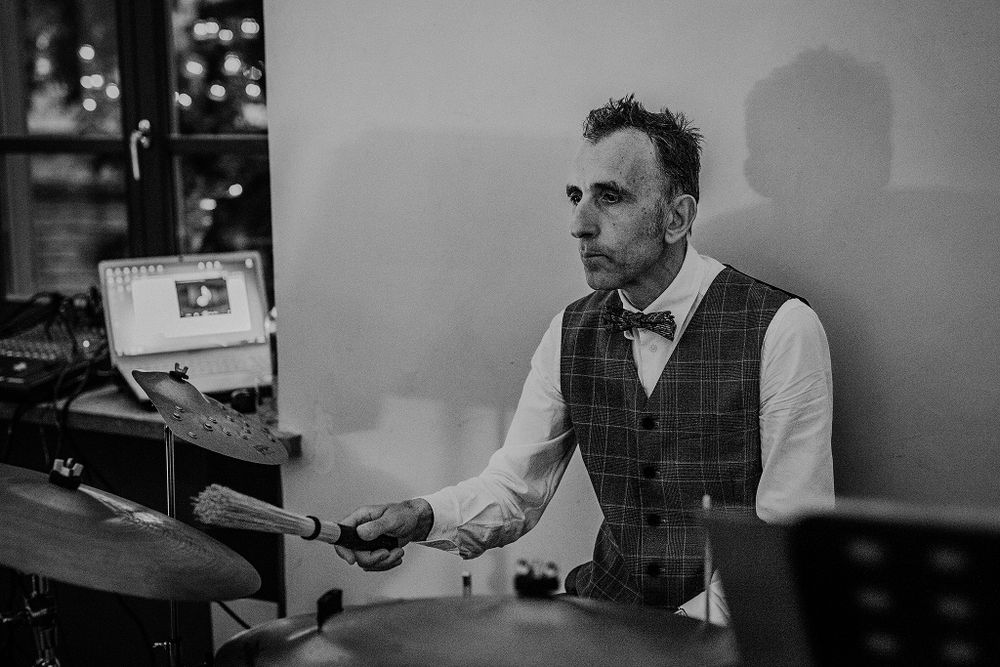 Black and white photo of male DJ performing at wedding reception in vest and bow tie.