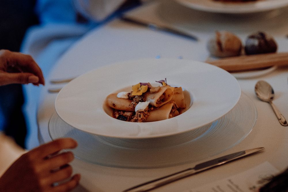 Elegant gourmet dish served in white bowl at wedding reception dinner table.