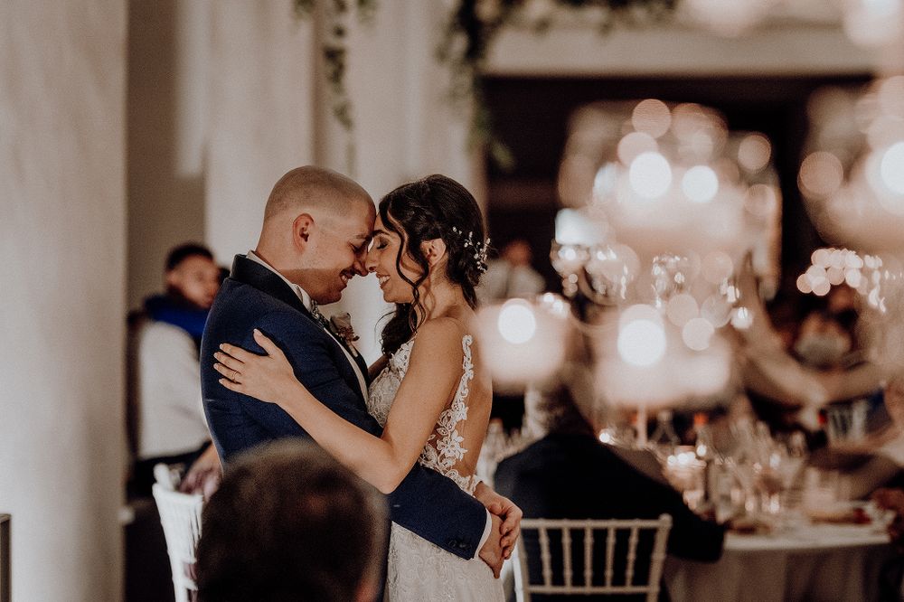 Bride and groom sharing romantic first dance in softly lit wedding reception venue.