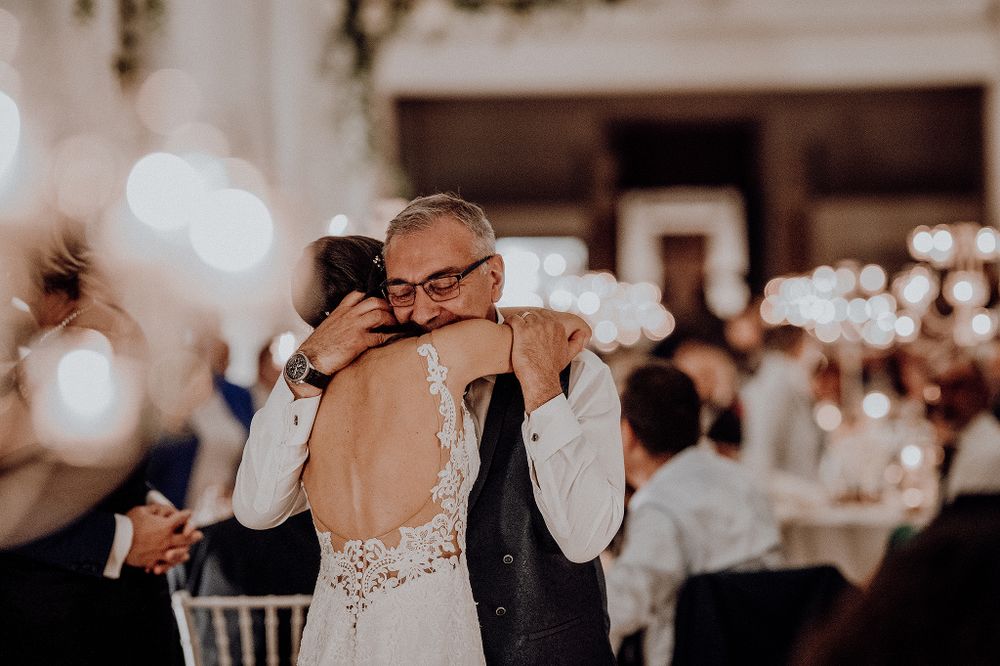Bride sharing emotional hug with father during wedding reception on the dance floor.