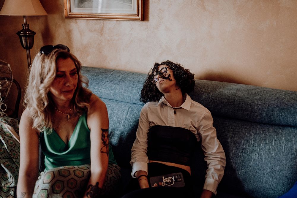 Young woman in green dress and man with curly hair relaxing on blue sofa.
