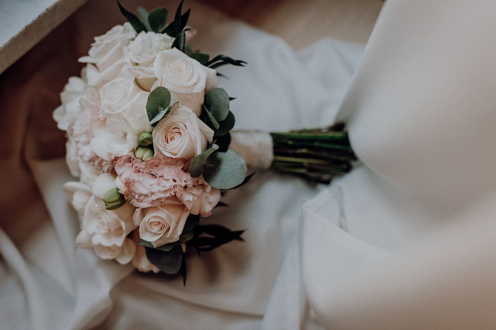 Elegant bridal bouquet of white and blush pink roses on soft ivory fabric.