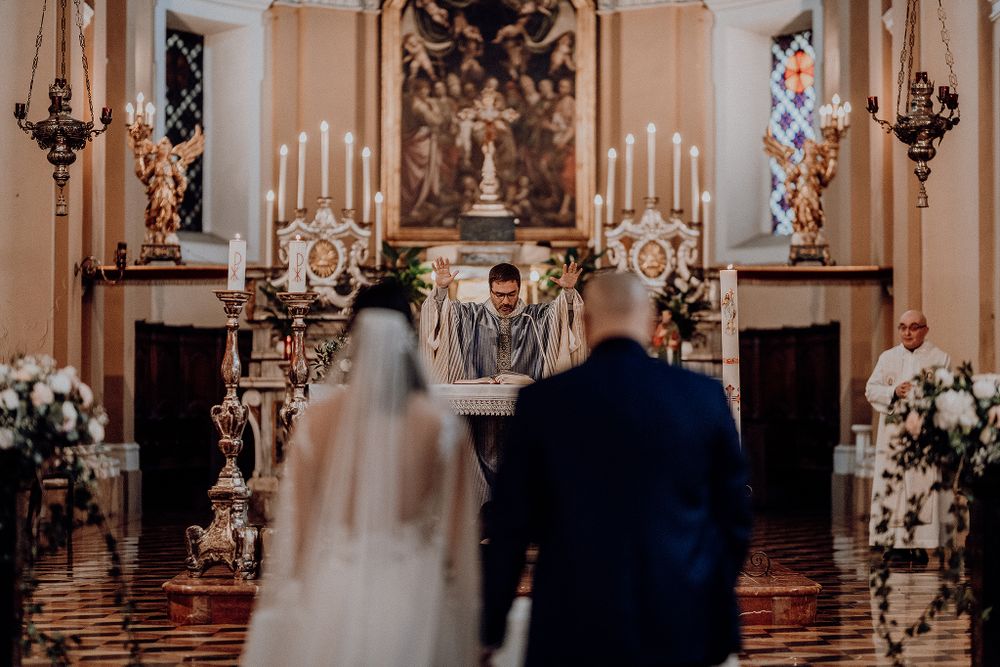 Bride and groom standing before priest at ornate church altar during wedding ceremony.