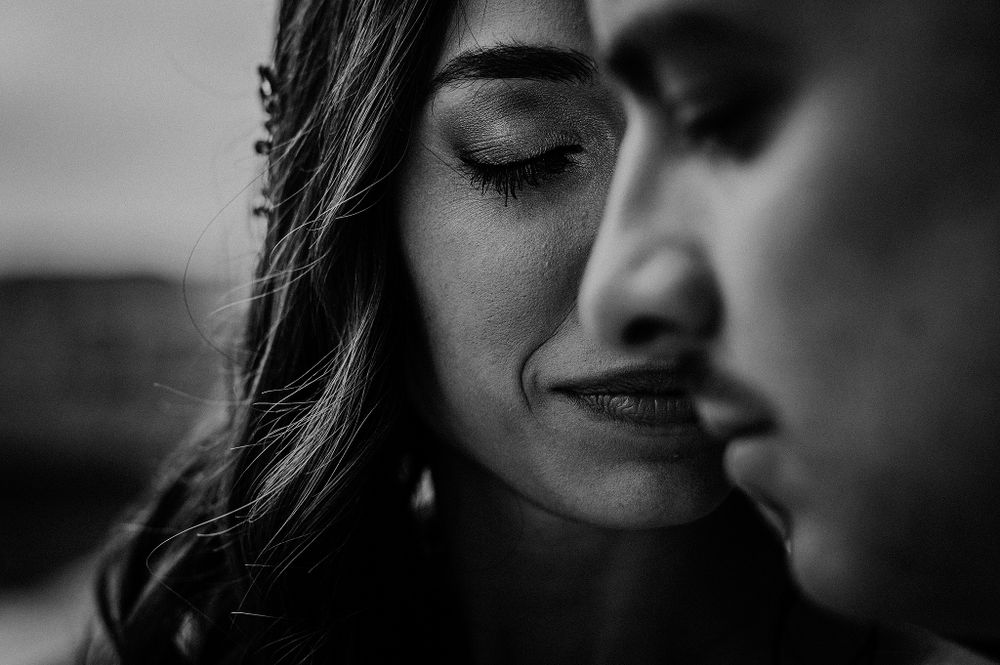 Intimate black and white close-up portrait of a bride with closed eyes smiling softly beside her partner.