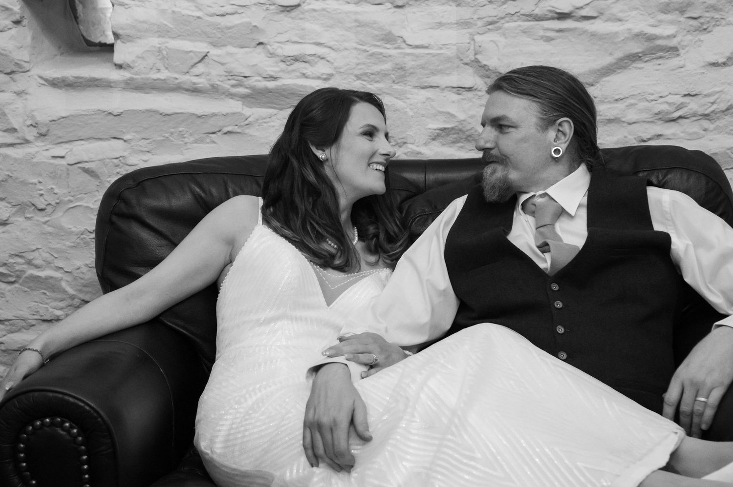 Intimate black and white photo of wedding guests relaxing on sofas.