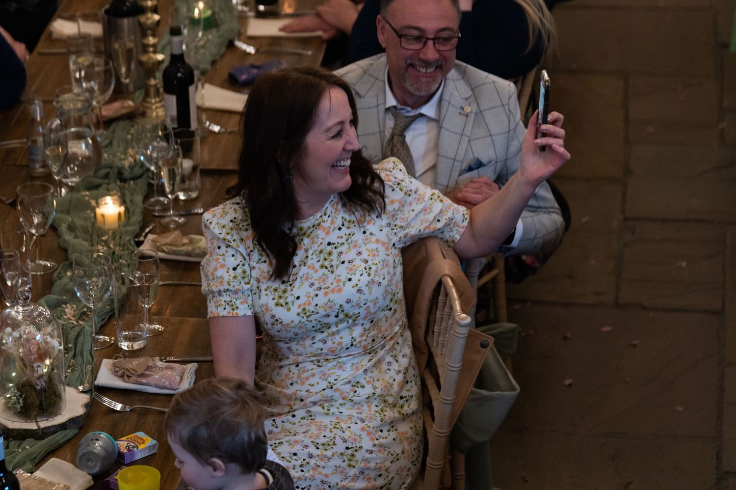 Wedding guests enjoying a reception dinner in a rustic barn setting.