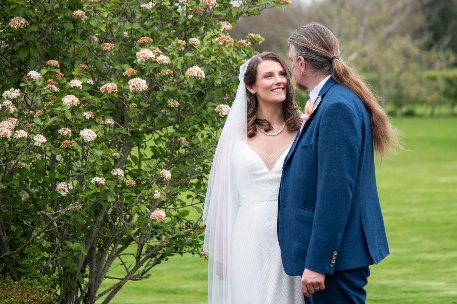 Climbing roses and greenery create a romantic garden backdrop near a wooden fence.