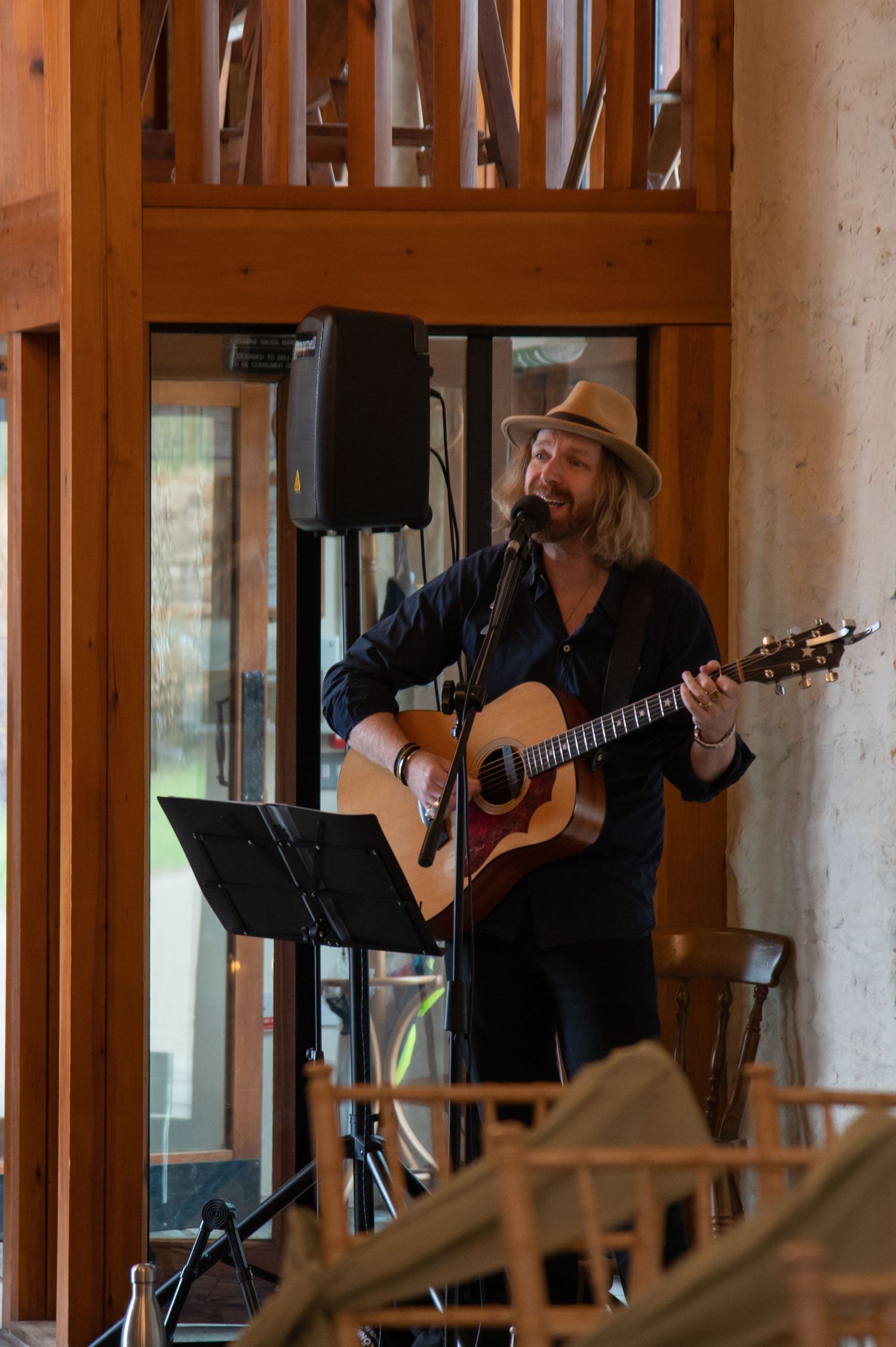 A musician performs with an acoustic guitar in a wooden-beamed venue.