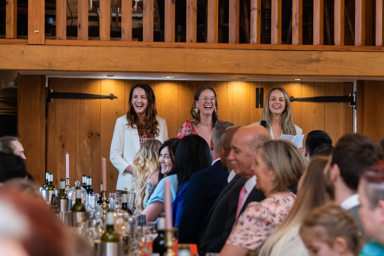 Interior of a barn wedding venue with warm lighting and wooden beams.
