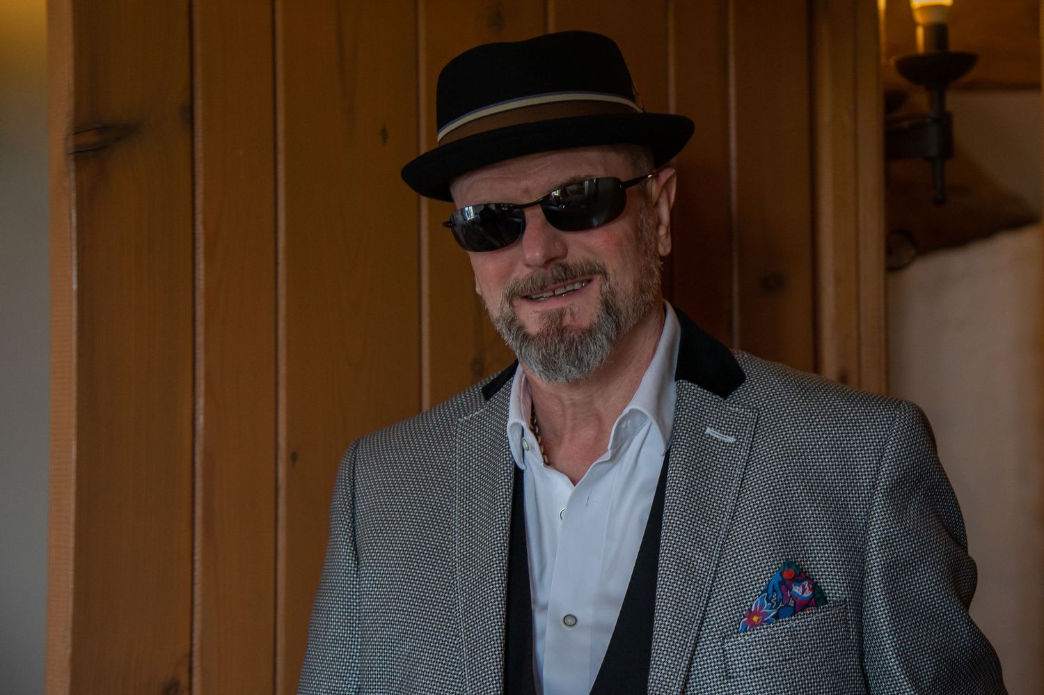 Stylish wedding guests in formal attire and hats gather indoors for celebration.