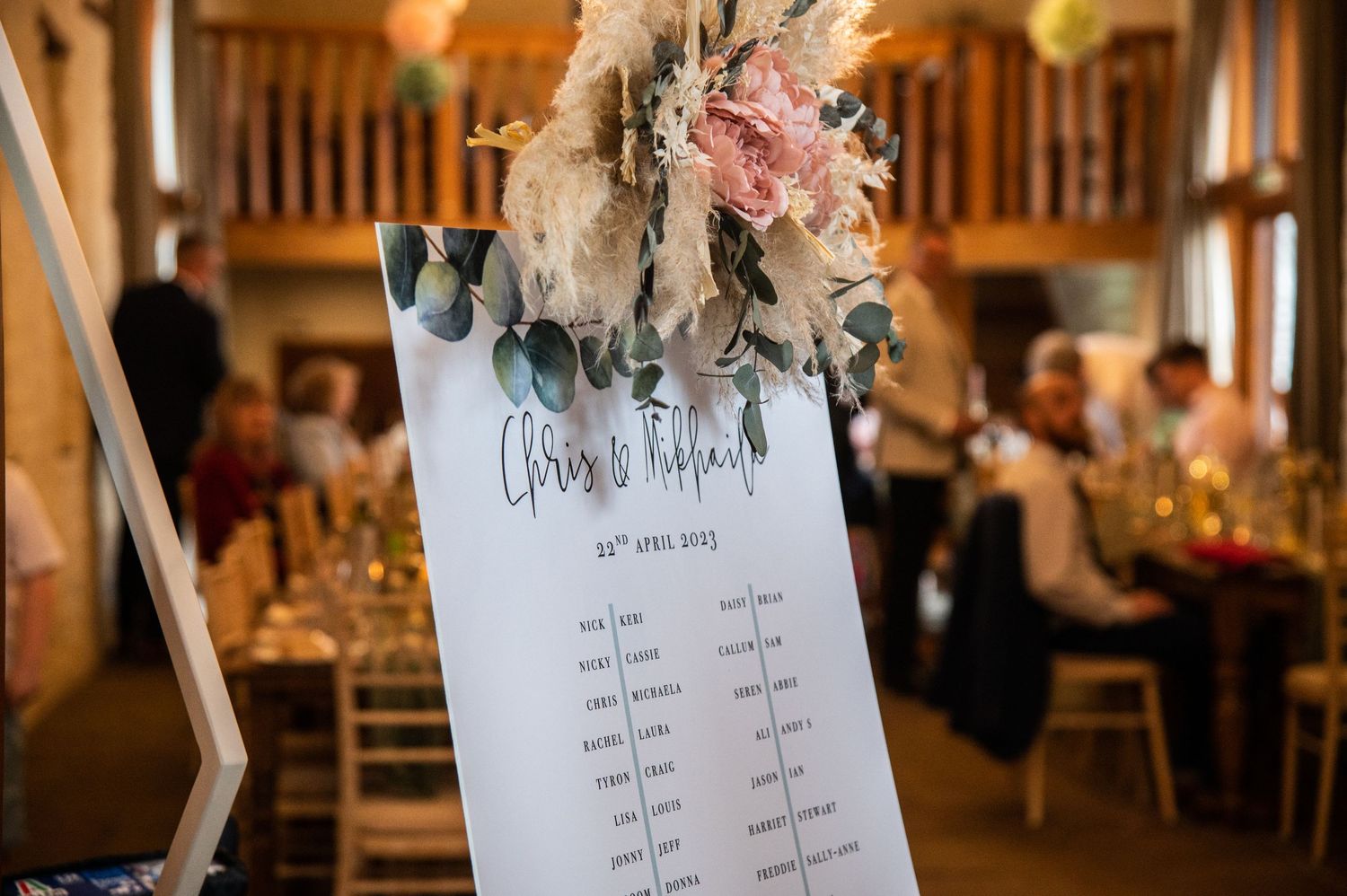 Wedding reception venue with wooden beams and decorative seating arrangements.
