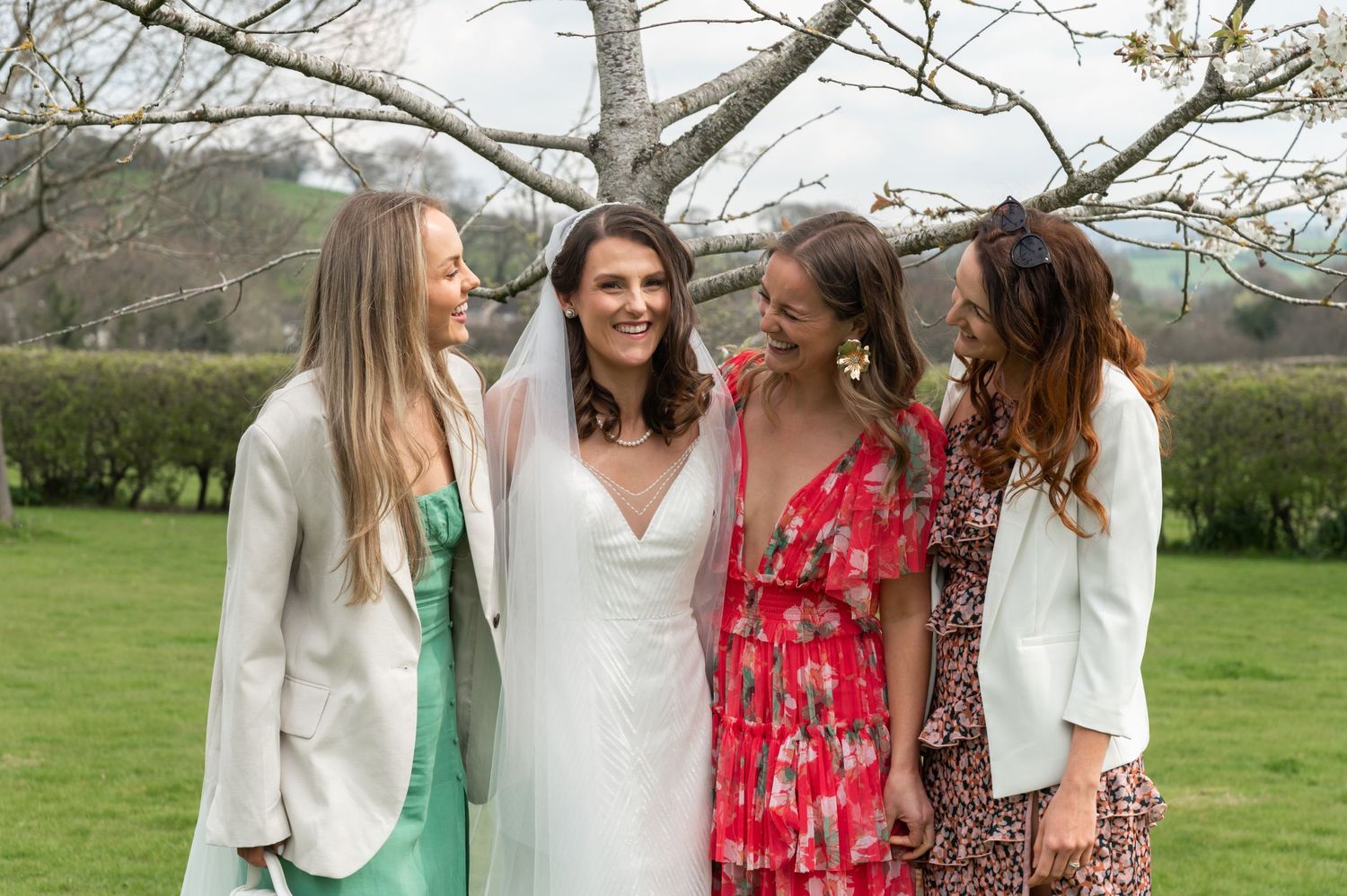 Bridesmaids in colorful dresses pose together outdoors.