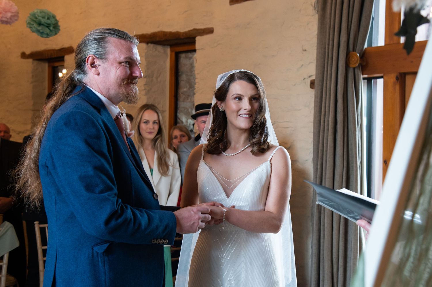 Wedding ceremony moments captured against a rustic indoor backdrop.
