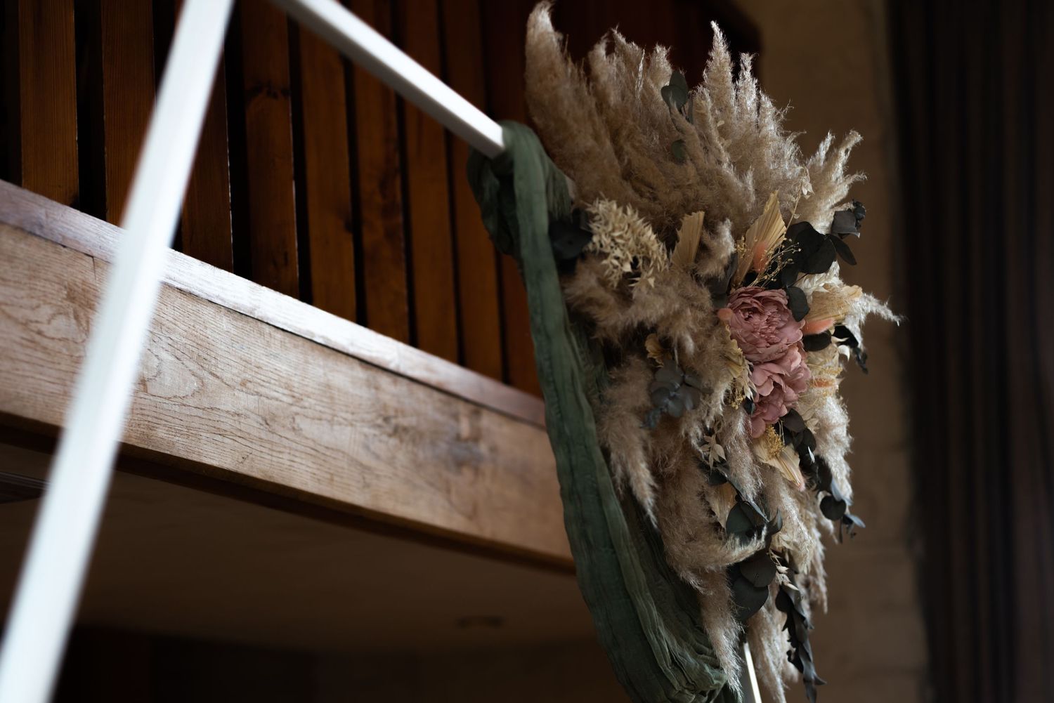Rustic wooden beams with dried floral decorations in a barn venue.