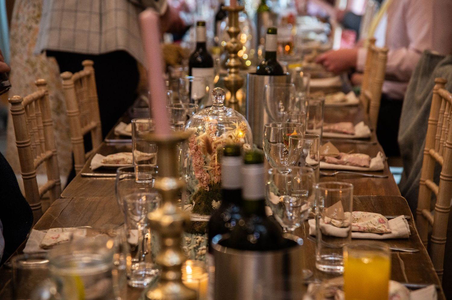 Elegant table settings at a rustic wedding reception with glassware and candles.