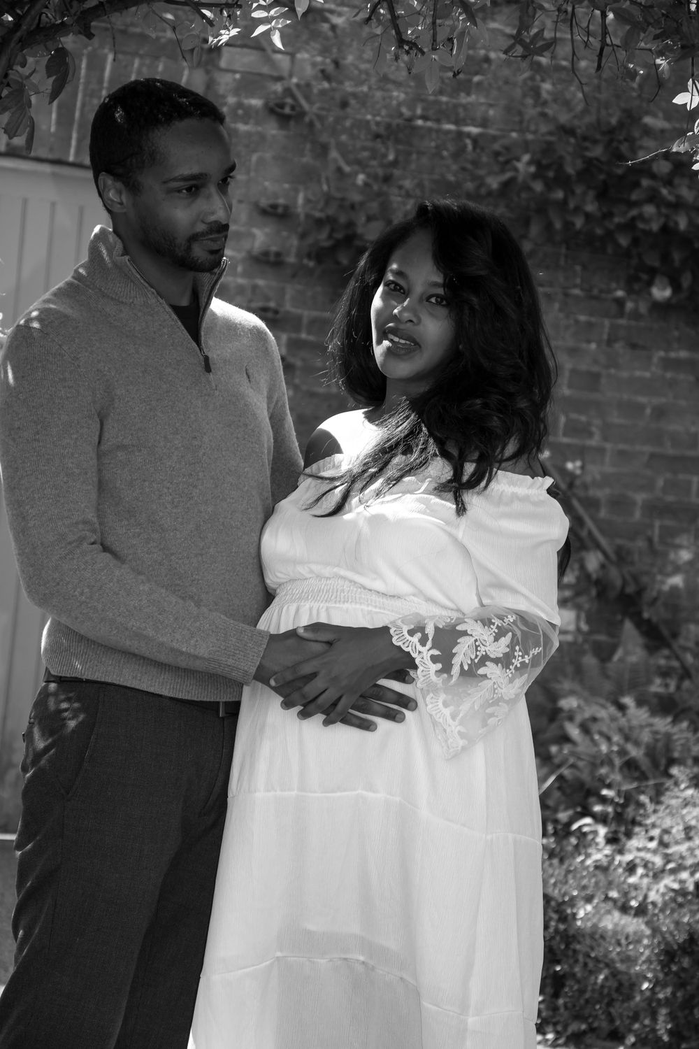 Intimate black and white maternity portrait with couple in casual formal wear.