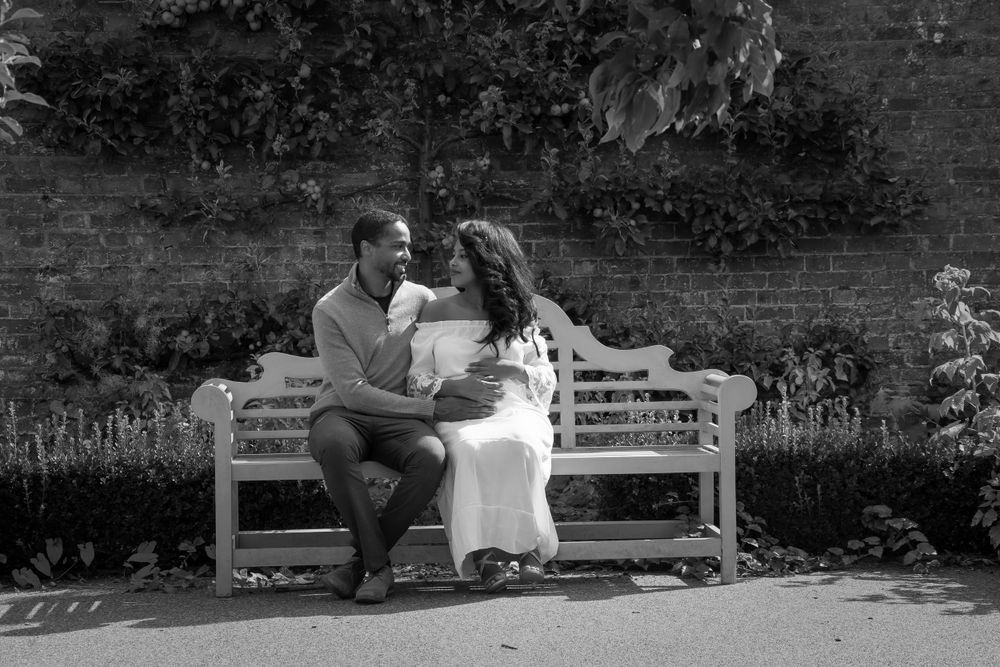 Couple sharing an intimate moment on a wooden bench in black and white photography.