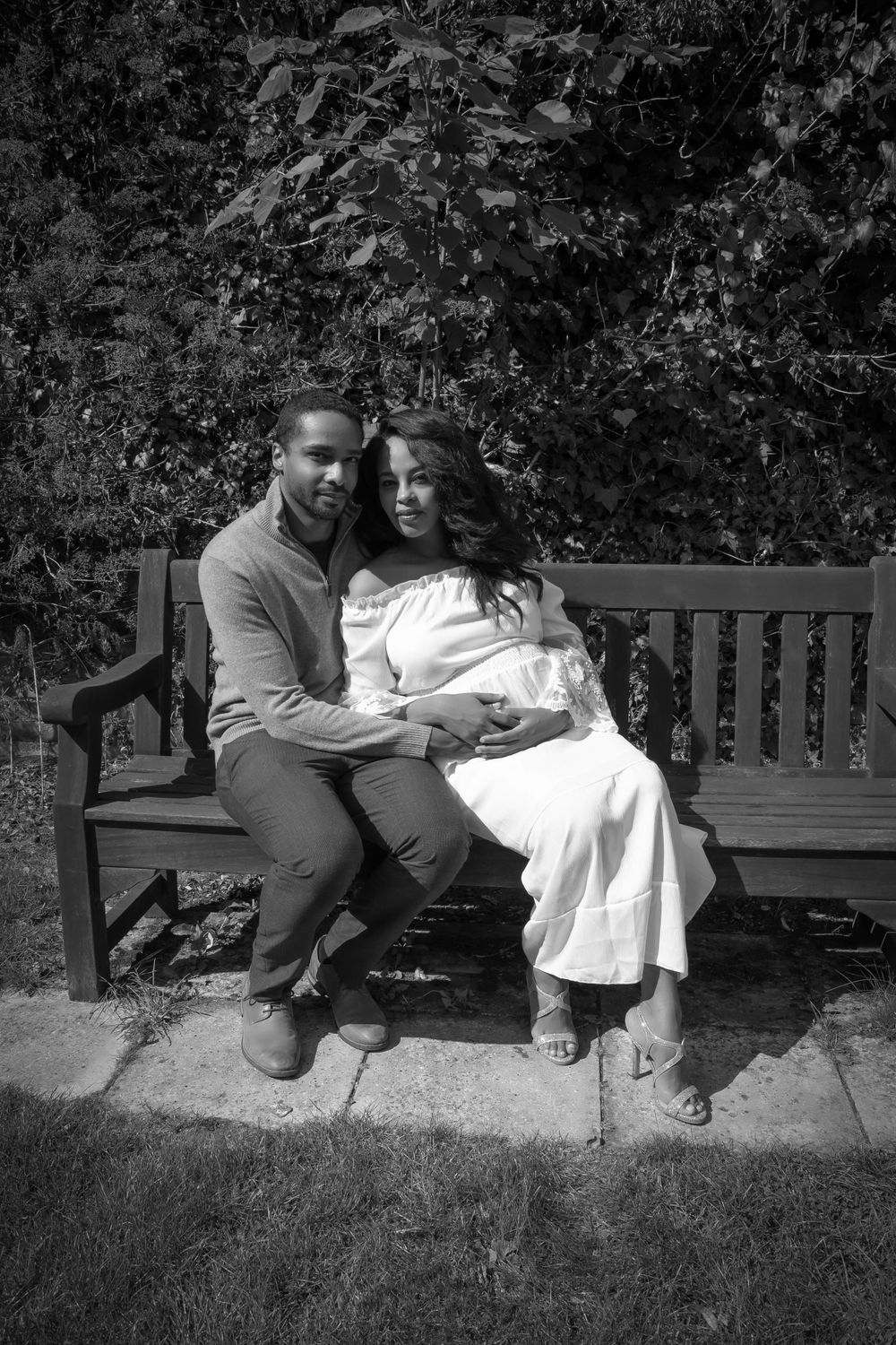 Romantic black and white photo of a couple embracing on a garden bench.
