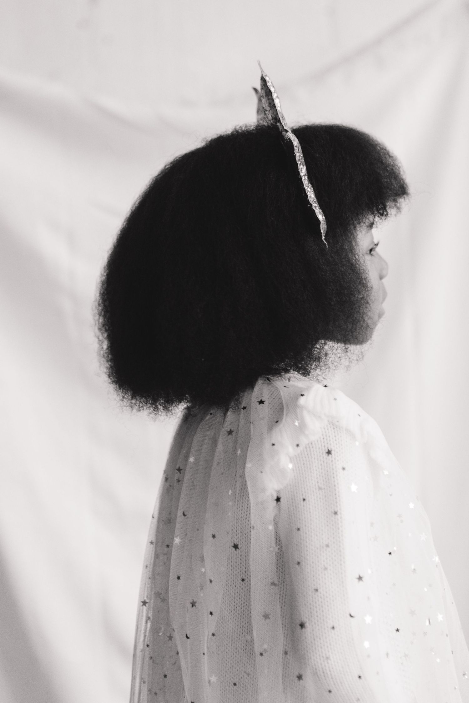 Capturing Holiday Happiness: Little Girl's Candid Smile in a Studio Session with Tulle Cape and Star Headband