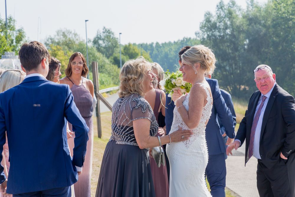 Wedding guests gather outdoors for a celebration on a sunny summer day.