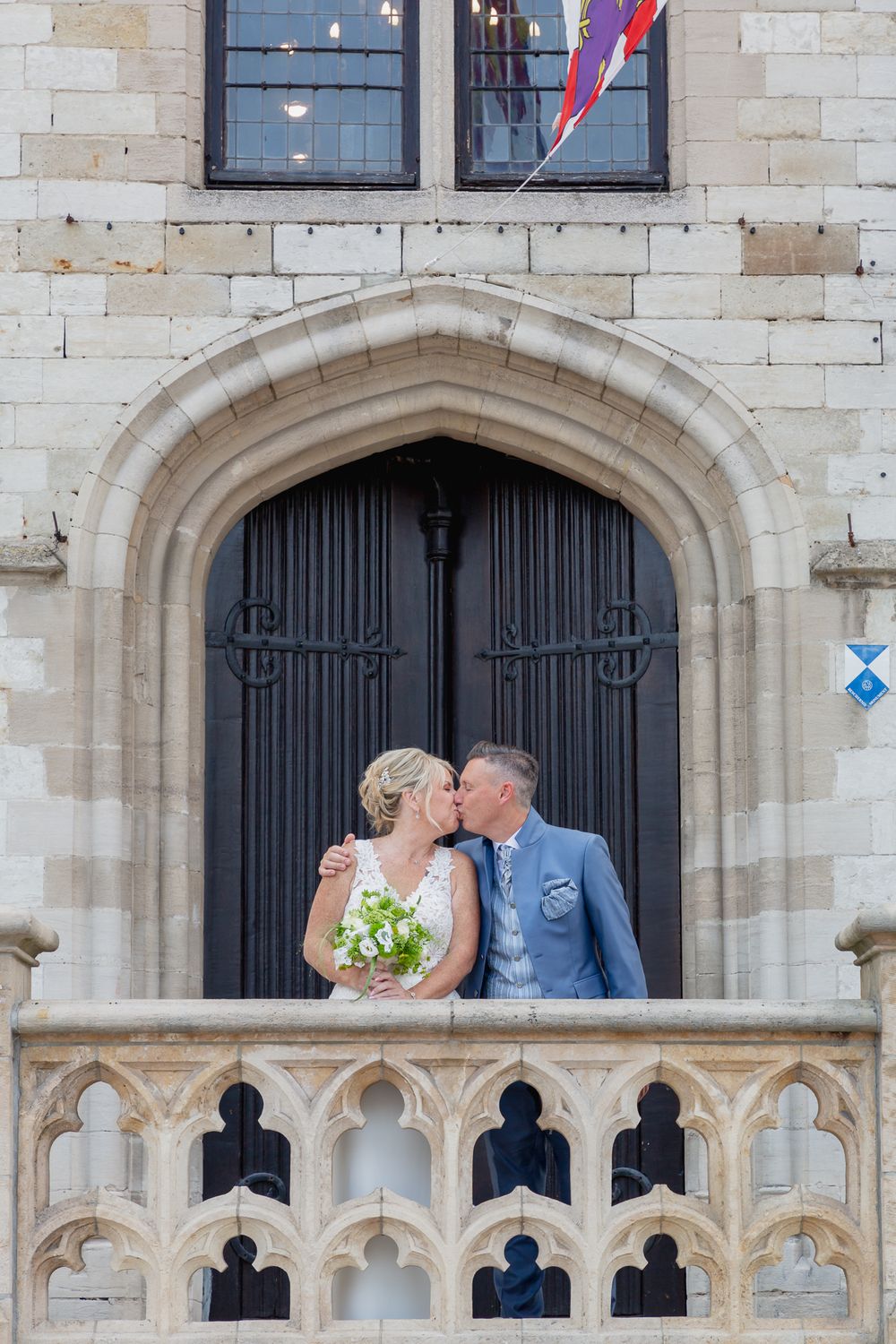 A romantic moment captured on a gothic stone balcony with ornate architectural details.