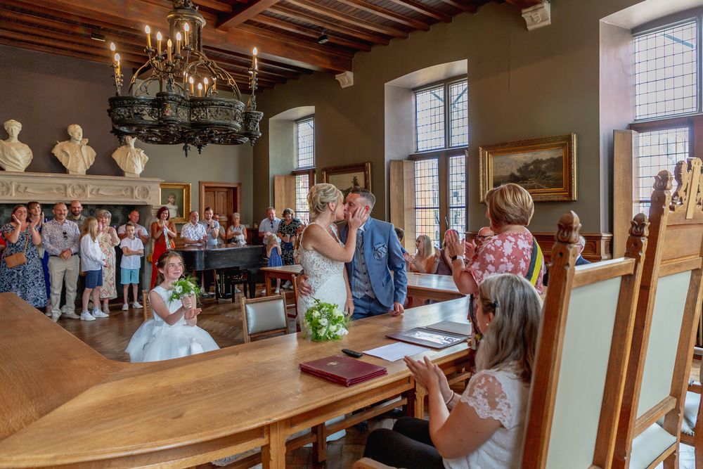 Wedding ceremony takes place in an elegant historic room with wooden beams and chandeliers.