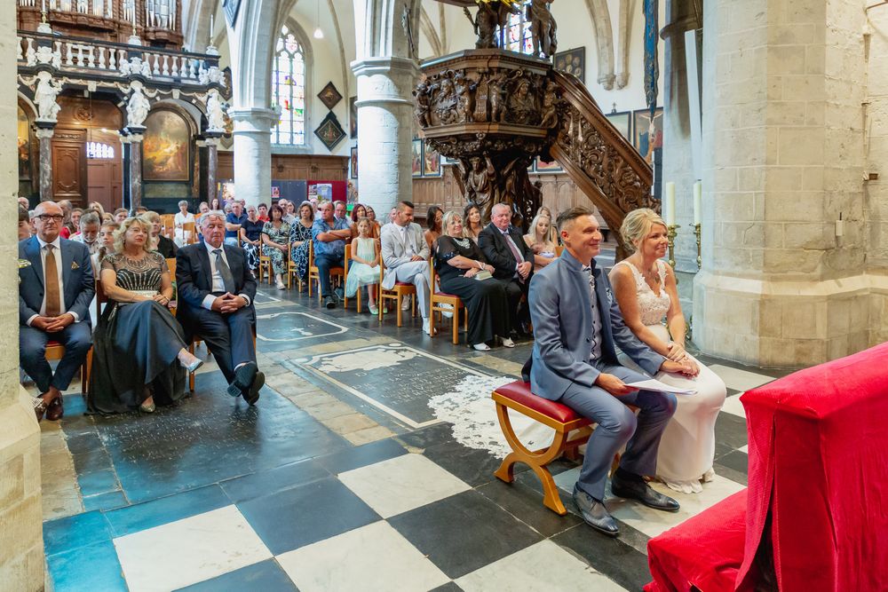 Wedding ceremony inside a historic church with checkered floors and wooden pews.