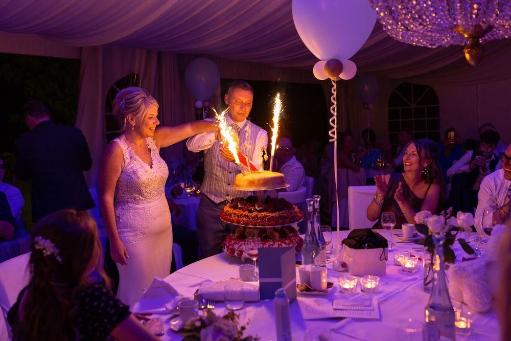 Couple cutting their wedding cake under purple lighting at an elegant reception.