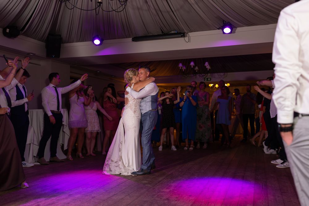 First dance moment at wedding reception with purple mood lighting.