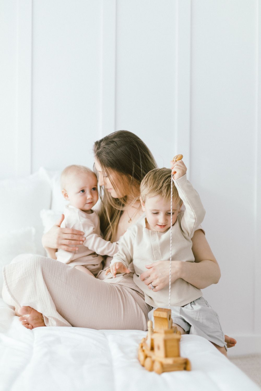 Joyful family moment with wooden blocks during playtime on white bedding.