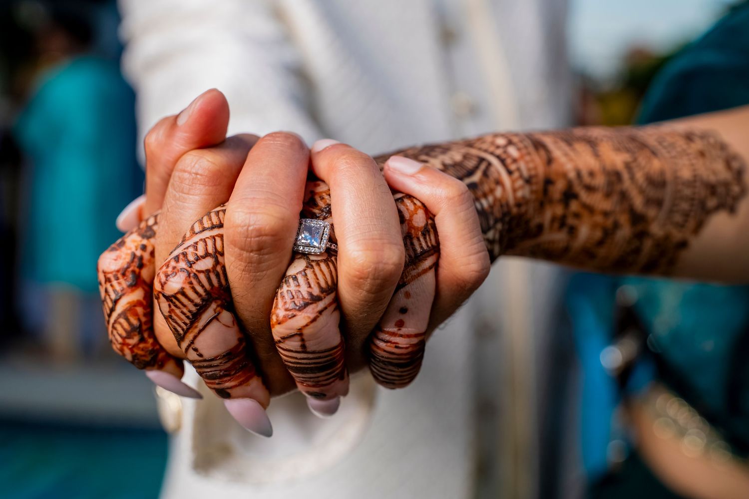 Close-up of hands adorned with intricate henna mehndi designs clasped together.