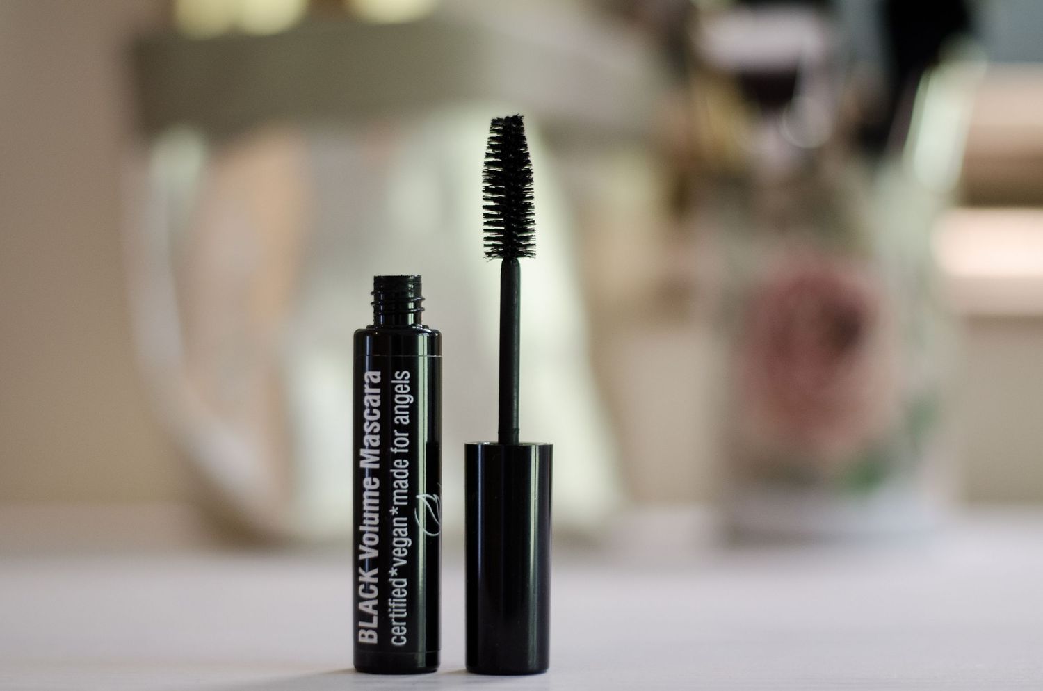 Black mascara wand and tube photographed in soft focus.