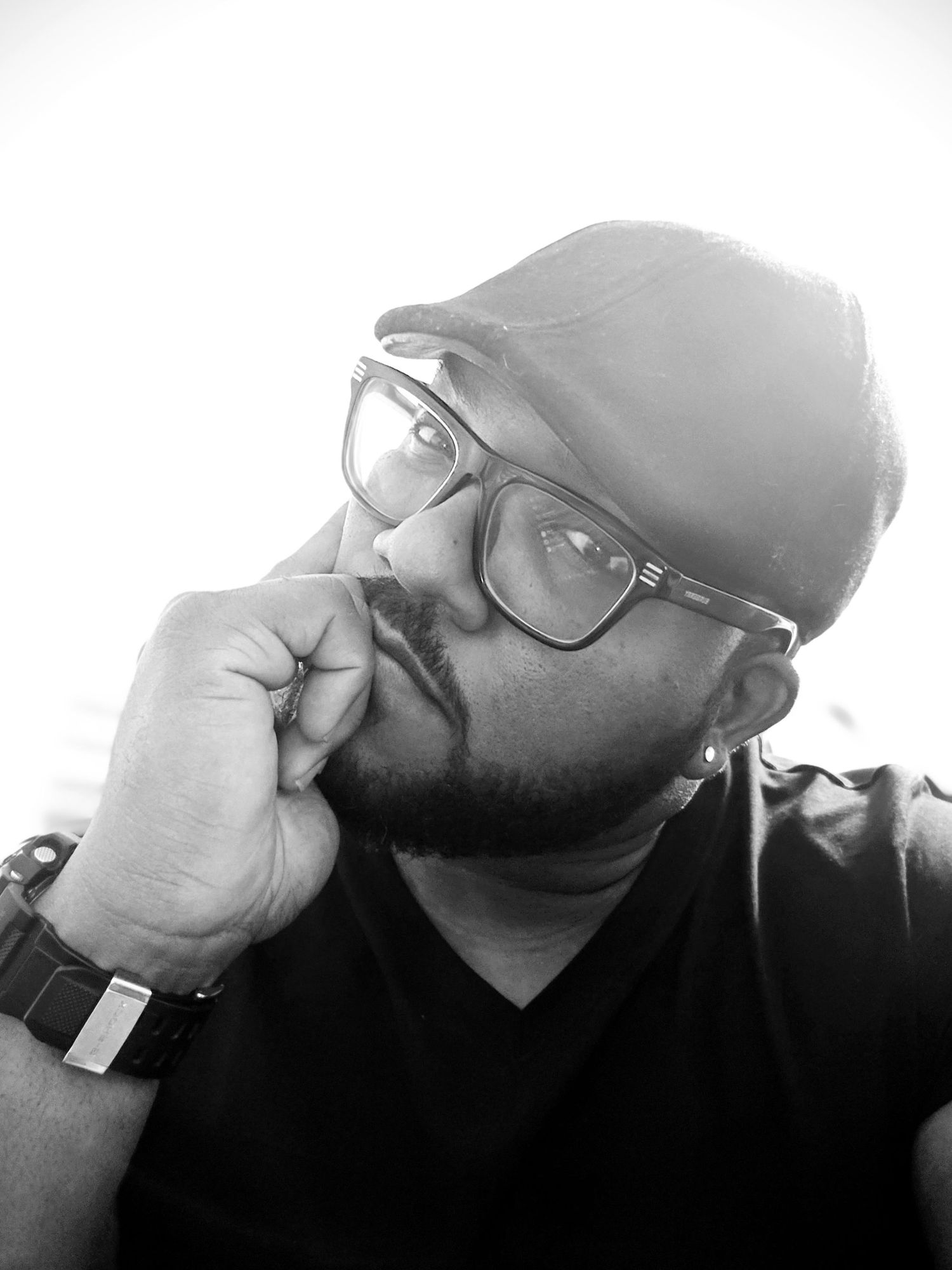 Black and white selfie of person wearing glasses and beanie in contemplative pose.